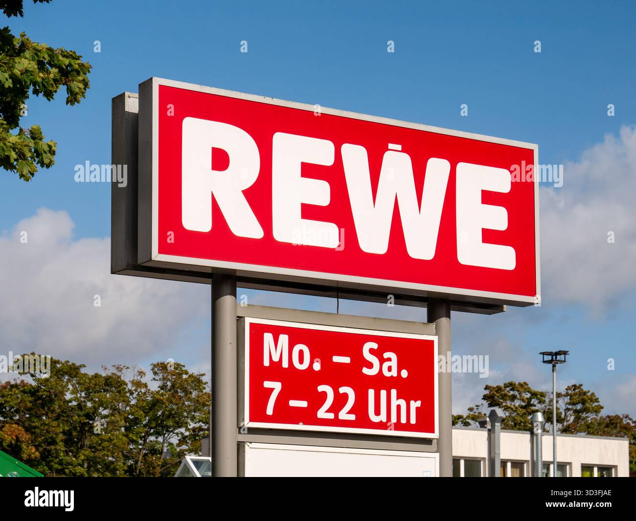 REWE-Schild mit Öffnungszeiten am Eingang eines Supermarktes in Kiel Stockfoto