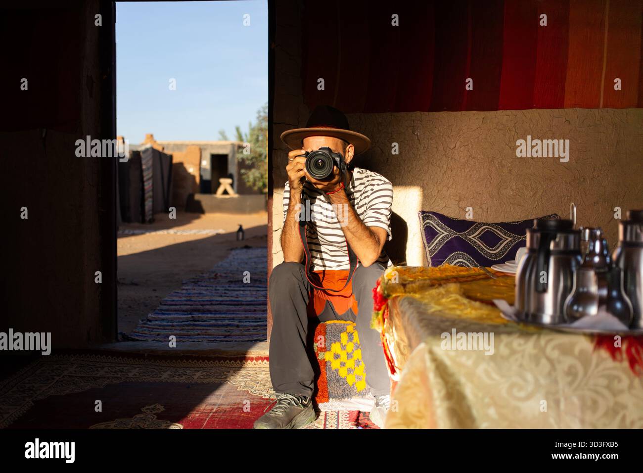 Ein Mann fängt die Schönheit der Sahara in einem traditionellen Berberzelt in Merzouga, Marokko, ein. Das warme Ambiente zeigt marokkanische Kultur Stockfoto