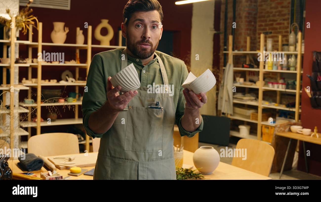 Verängstigt schockierter kaukasischer Geschäftsmann männlicher Mann Geschäftsmann Verkäufer Töpfer Keramiker Künstler mit Händen gebrochene Vase Porzellan Schüssel Keramik Kunsthandwerk Kunst Stockfoto