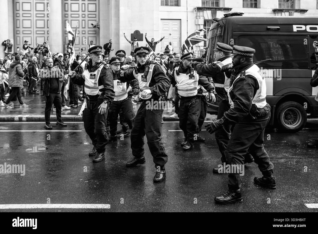 Polizeibeamte ziehen Schlagstöcke während der von Tommy Robinson organisierten Rallye Unite the Kingdom. Stockfoto