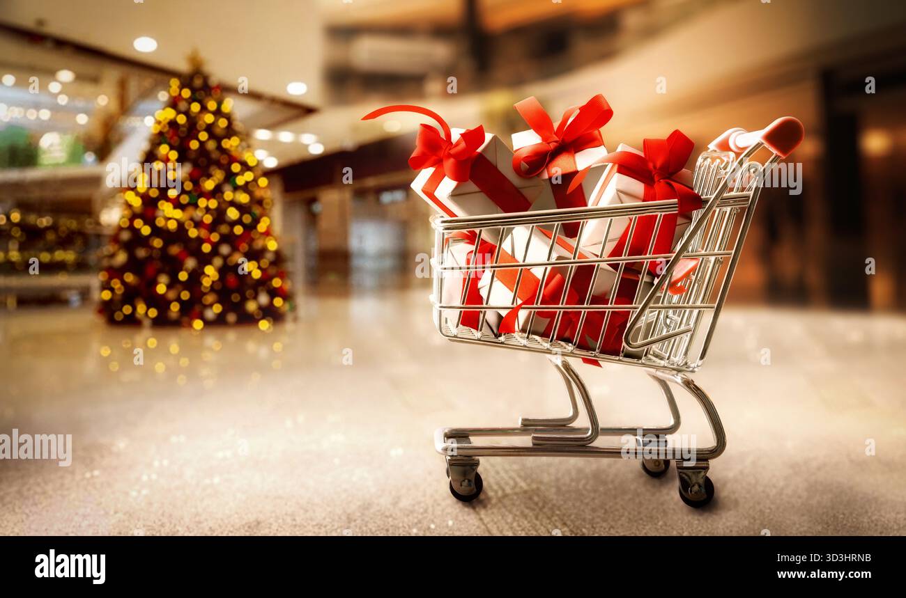 Einkaufskonzept für Weihnachtsgeschenke mit Einkaufswagen voller Geschenkpakete in weißem Papier und rotem Band im Einkaufszentrum. Stockfoto