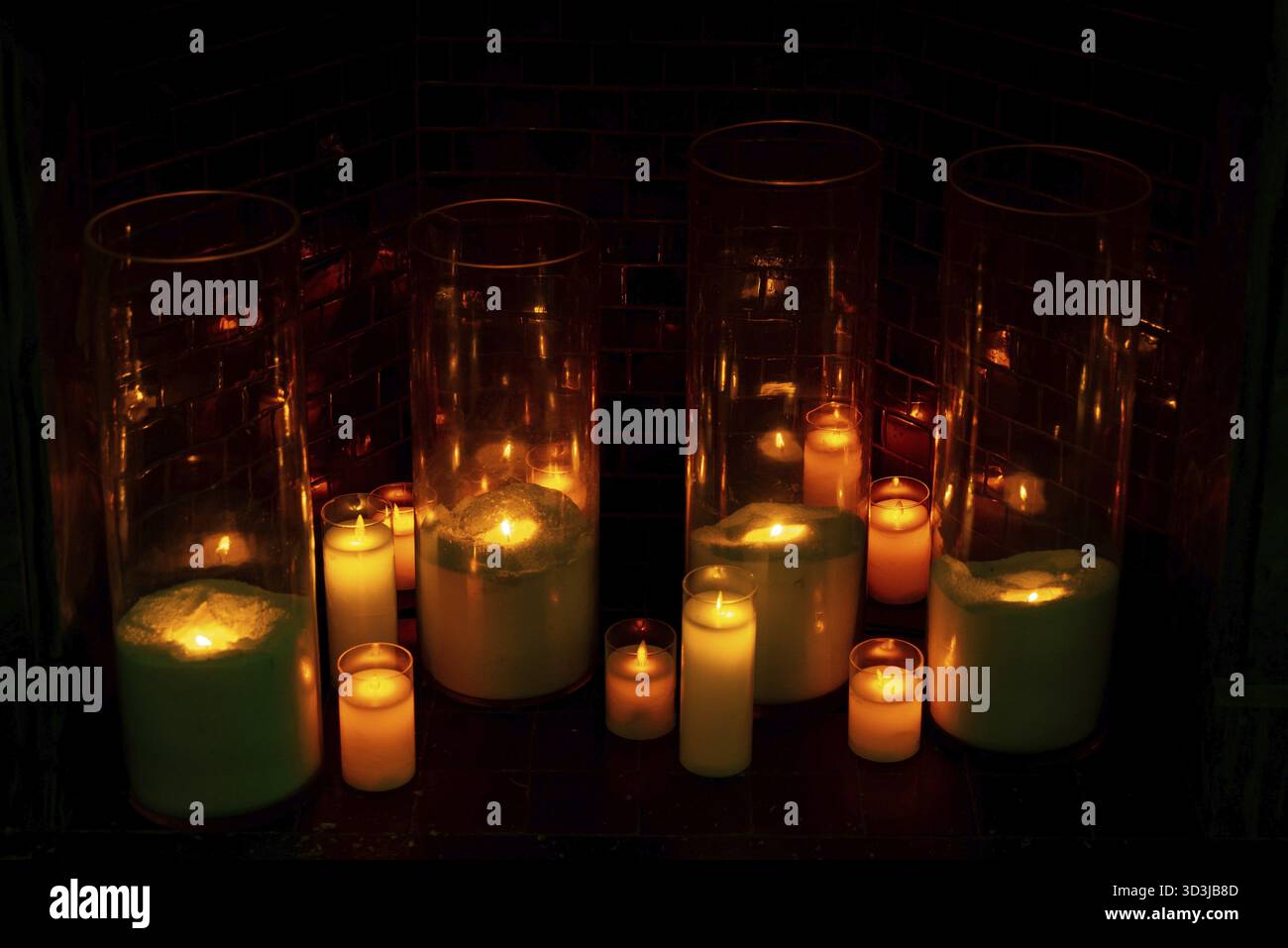 Essen, warme Glühkerzen in hohen Glaszylindern schaffen ein gemütliches und romantisches Ambiente in einem schwach beleuchteten Raum Stockfoto