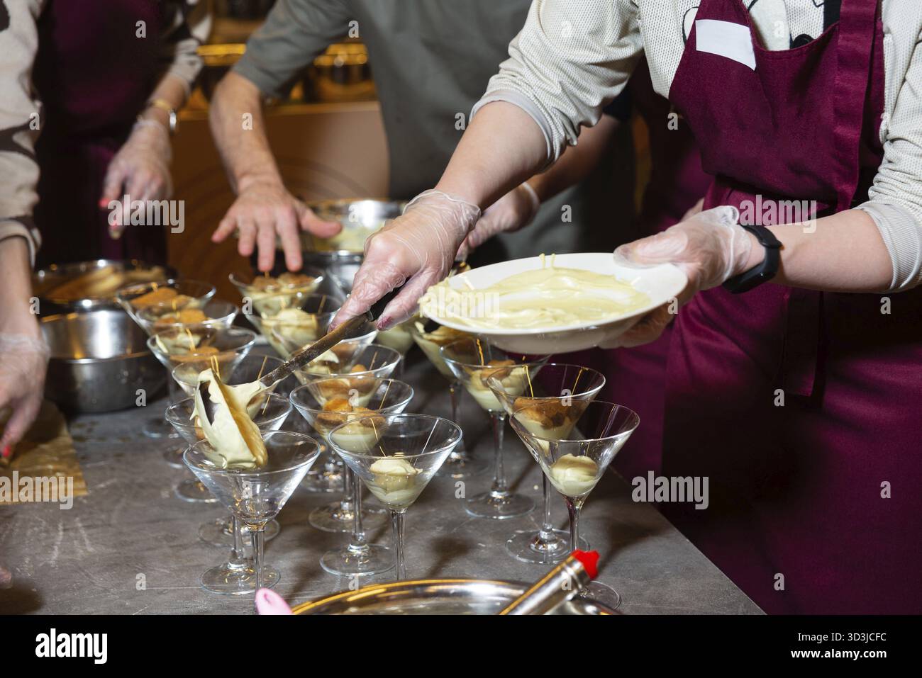 Essen, Hände in Handschuhen servieren cremiges Dessert in Martini-Gläsern während eines kulinarischen Kurses oder einer Küchenzubereitungsveranstaltung Stockfoto