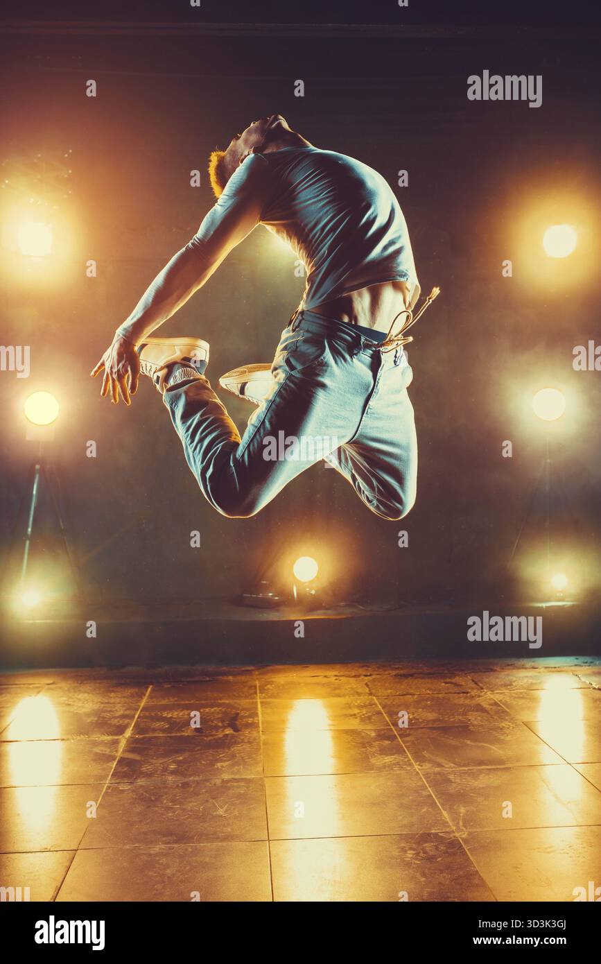 Junger Mann tanzt im Club mit Licht und Rauch. Warme Farben Stockfoto