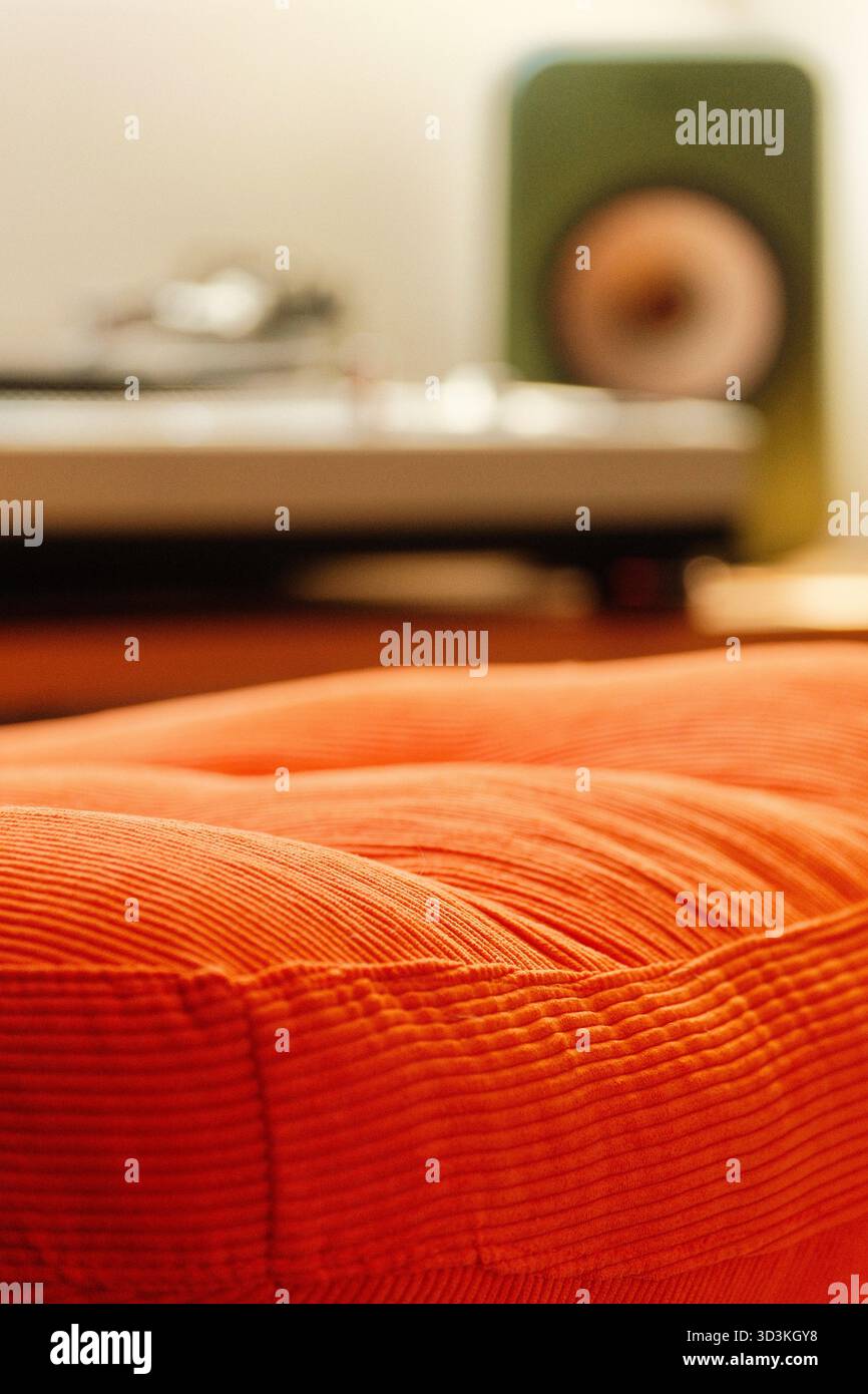 Herrlicher orangener Sessel aus den 70er Jahren mit Musik im Hintergrund. Stockfoto