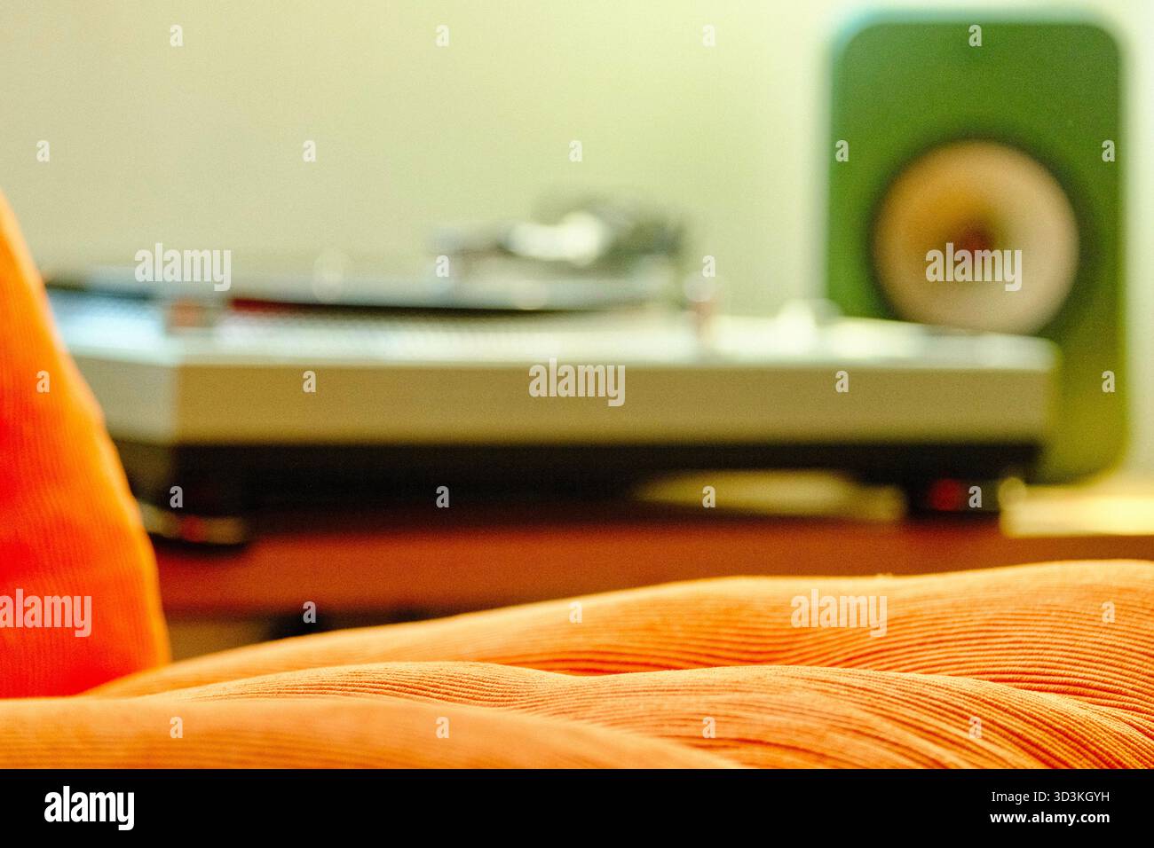 Herrlicher orangener Sessel aus den 70er Jahren mit Musik im Hintergrund. Stockfoto