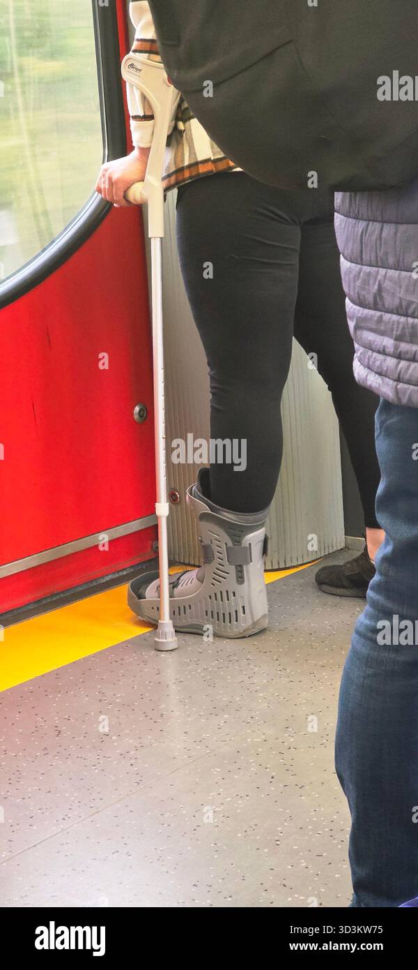 Individual steht in einem öffentlichen Nahverkehr, mit Mobilitätshilfen, die den städtischen Pendelverkehr und die Zugänglichkeit im Alltag demonstrieren. - Smartphone-aufgenommenes Stockfoto