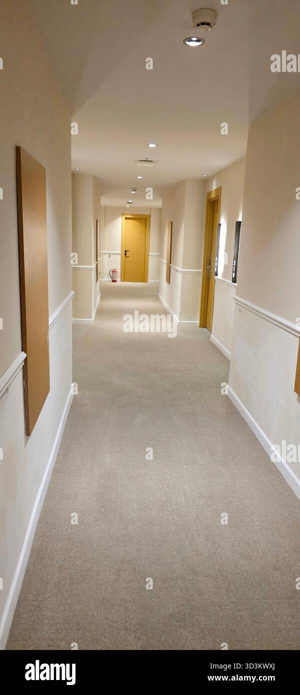 . Der lange Korridor verfügt über sanfte Beleuchtung und Wände in neutralen Farben, die eine ruhige und einladende Atmosphäre für Gäste und Besucher schaffen Stockfoto
