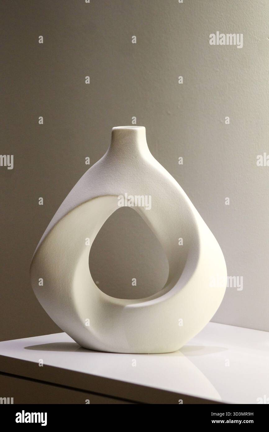 Künstlerische weiße Keramikvase mit skulpturaler Form und glatter matter Textur, ideal für moderne oder skandinavische Wohnkultur. Stockfoto