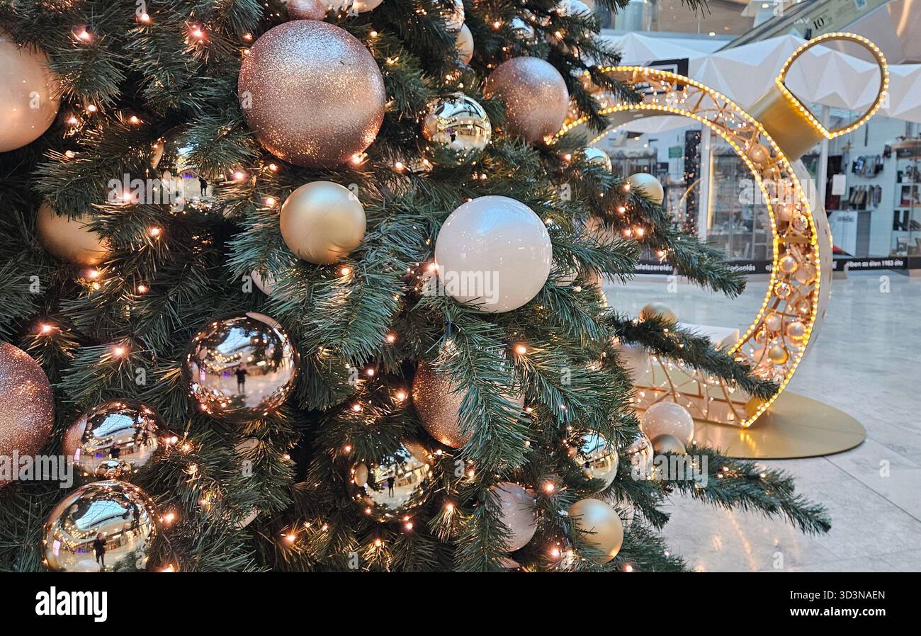 Nahaufnahme von Rosegold-, Gold- und cremefarbenen Kugeln auf einem geschmückten Weihnachtsbaum in einem Einkaufszentrum in Budapest, Ungarn namens Allee Stockfoto