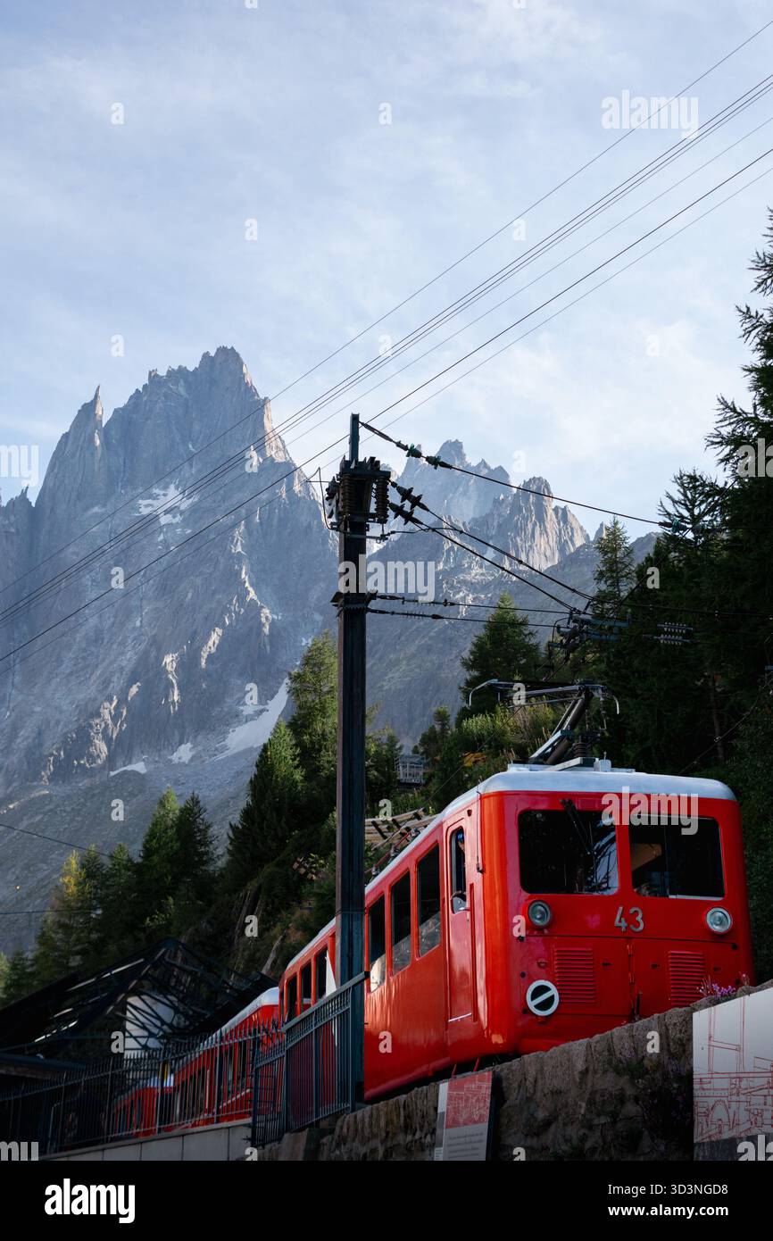 Historische Bergbahn, die durch den Wald mit dramatischen Felsspitzen dahinter fährt Stockfoto