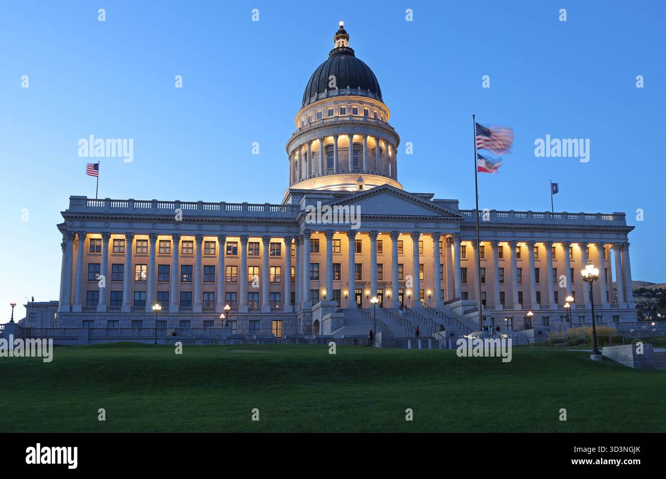 Utah State Capitol beleuchtet in der Abenddämmerung mit grünem Gras im Vordergrund Stockfoto