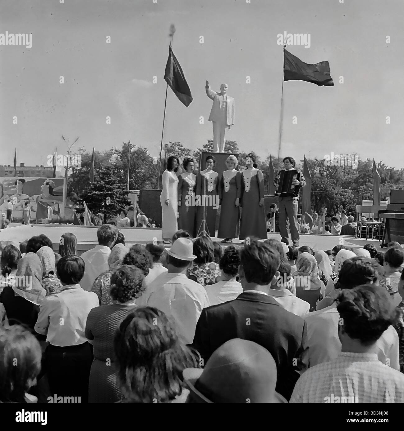 Ein Archivfoto vom 9. Mai 1975 in Sloviansk, ukrainische SSR. Auf dem zentralen Platz der Stadt findet ein öffentliches Konzert zum 30. Jahrestag des Sieges statt. Auf einer Bühne vor dem Lenindenkmal tritt ein weibliches Gesangsensemble, begleitet von einem Mann auf dem Akkordeon (Bajan), für eine große Menge auf. Zuschauer füllen den Platz und beobachten die Vorstellung. Diese Szene fängt die öffentliche Feier und die patriotische Atmosphäre eines großen sowjetischen Urlaubs im friedlichen Donbass vor dem Krieg ein. Stockfoto