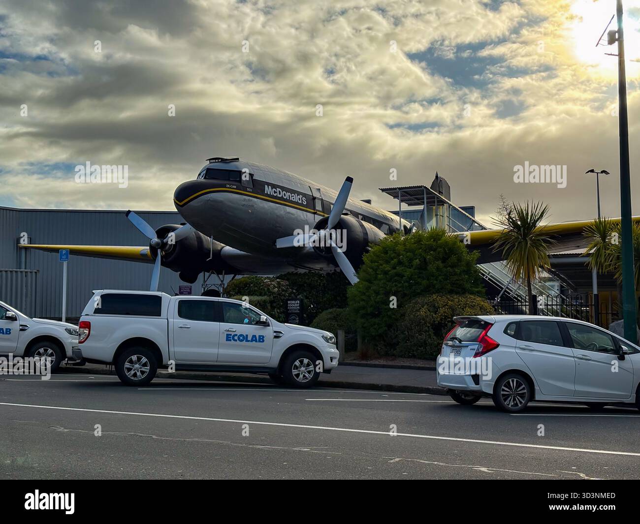 McDonald's Restaurant in Taupo, Neuseeland, einzigartig in einem stillgelegten DC-3-Flugzeug untergebracht. An einem bewölkten Tag parkten Autos entlang der Straße. Stockfoto