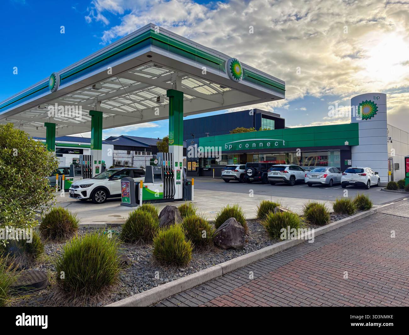 BP Tankstelle und BP Connect Supermarkt in Taupo, Neuseeland, mit Kraftstoffpumpen, geparkten Autos und Landschaftsgestaltung unter bewölktem Himmel. Ideal Stockfoto