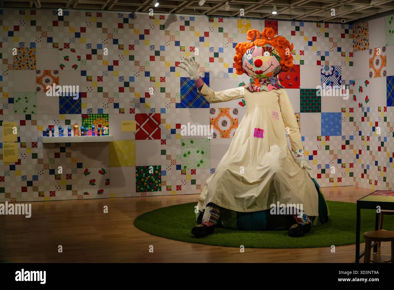 Janet Dawsons Kunstwerk zeigt eine große, farbenfrohe Puppe mit Patchwork-Gesicht und orangefarbenen lockigen Haaren in einem cremefarbenen Kleid Stockfoto