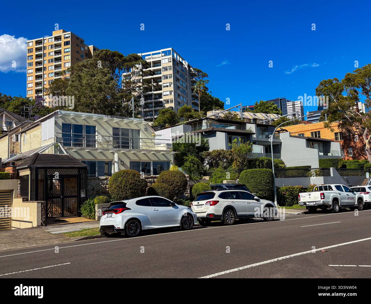 Wohnstraße in Waverton, Australien, mit einer Mischung aus Häusern und modernen Apartmenthäusern mit geparkten Autos unter klarem blauen Himmel. Stockfoto