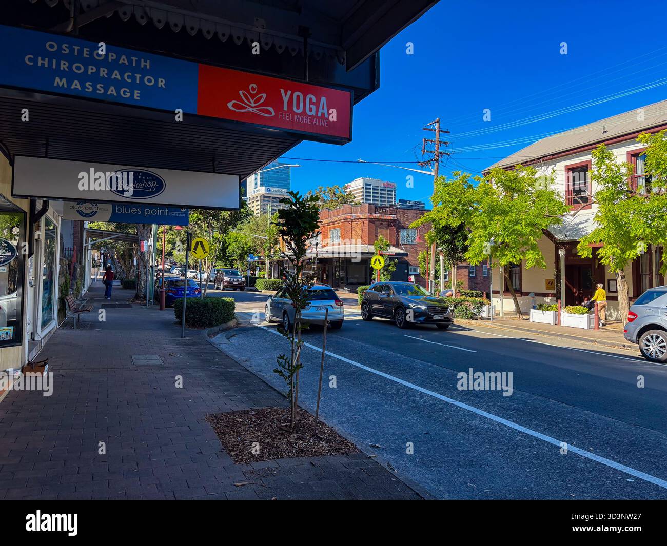 McMahons Point, Sydney, Australien, Straße mit lokalen Geschäften wie einem Buchladen, Yoga-Studio und Chiropraktik-Klinik. Autos auf der Straße, Fußgänger auf der Seite Stockfoto