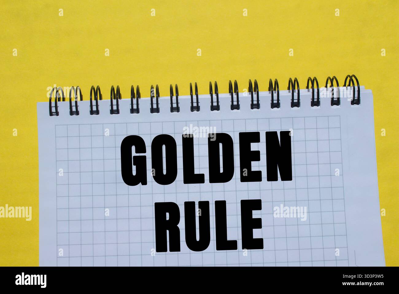 Goldene Regelmeldung auf Notizbuchseite auf gelbem Hintergrund geschrieben. Konzeptionelles goldenes Regelsymbol. Kopierbereich. Stockfoto
