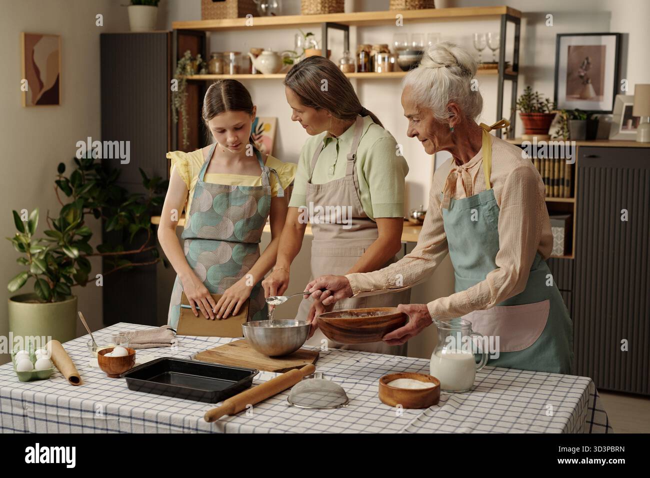 Kaukasisches Mädchen mit Mutter und Großmutter, die zusammen in der Küche backen Stockfoto