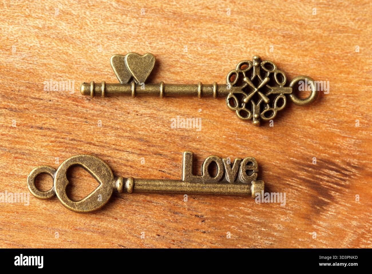 Dekorative Schlüssel mit Herzformen und Love-Inschrift auf hölzernem Hintergrund Stockfoto