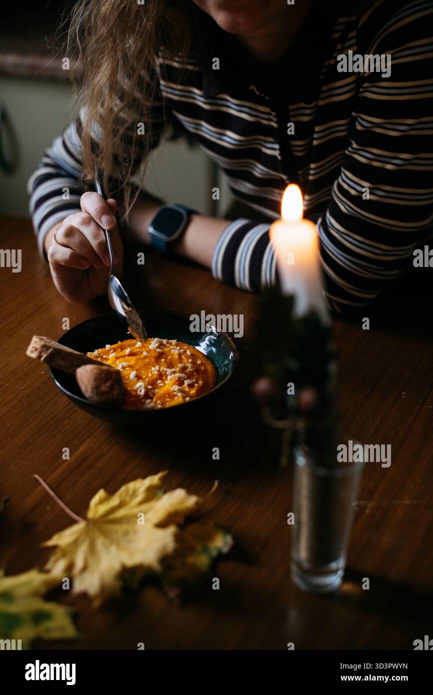 Kürbissuppe bei Kerzenlicht essen Stockfoto