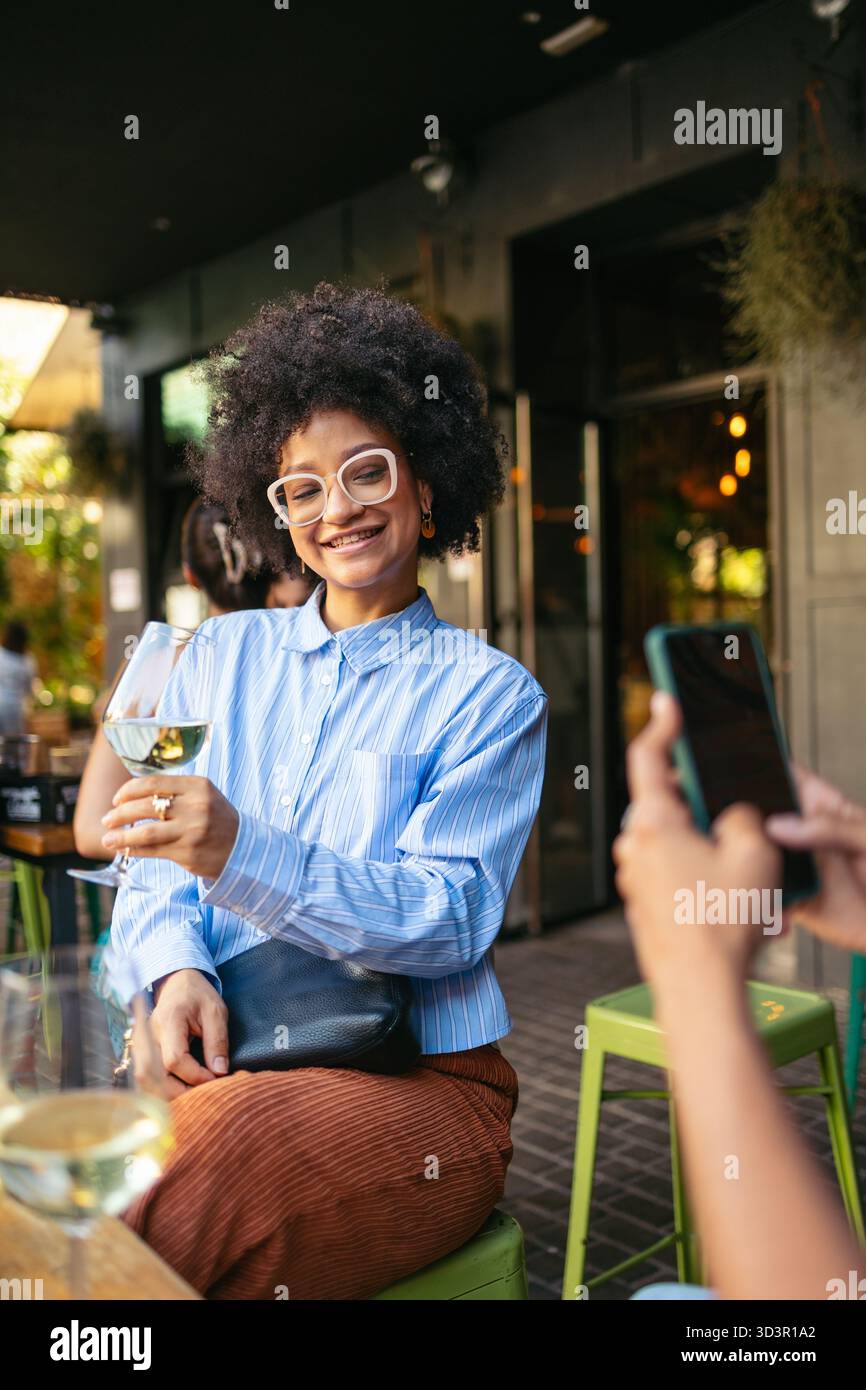 Zwei Freunde genießen einen lebhaften Nachmittag in der Innenstadt, wo sie lachen und trinken. Mit einem Smartphone können sie Erinnerungen festhalten und die Freude des urbanen Lebens genießen Stockfoto
