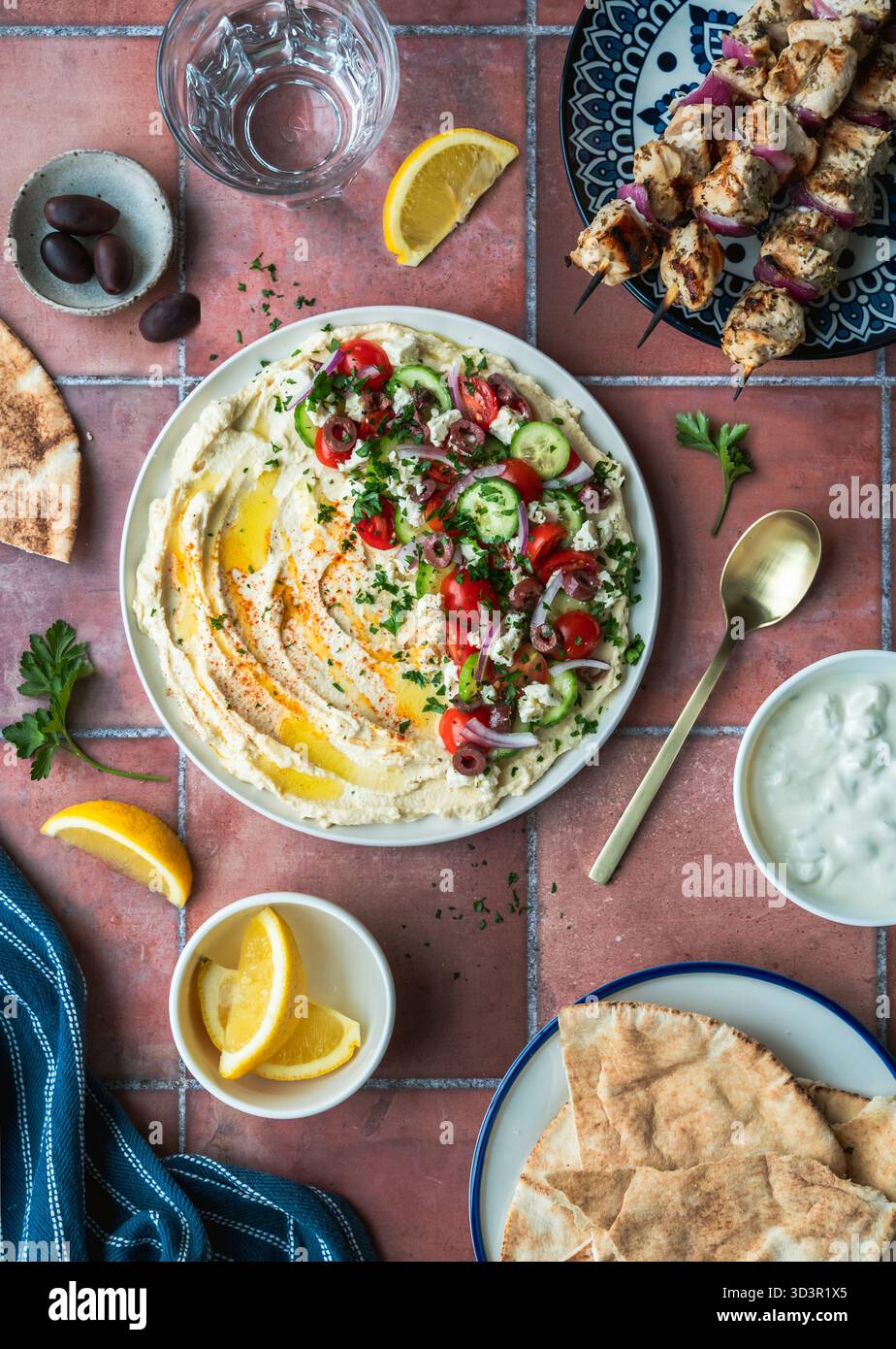 Blick von oben auf beladenen Hummus-Teller, Hühnchenkebabs und Pitas. Stockfoto