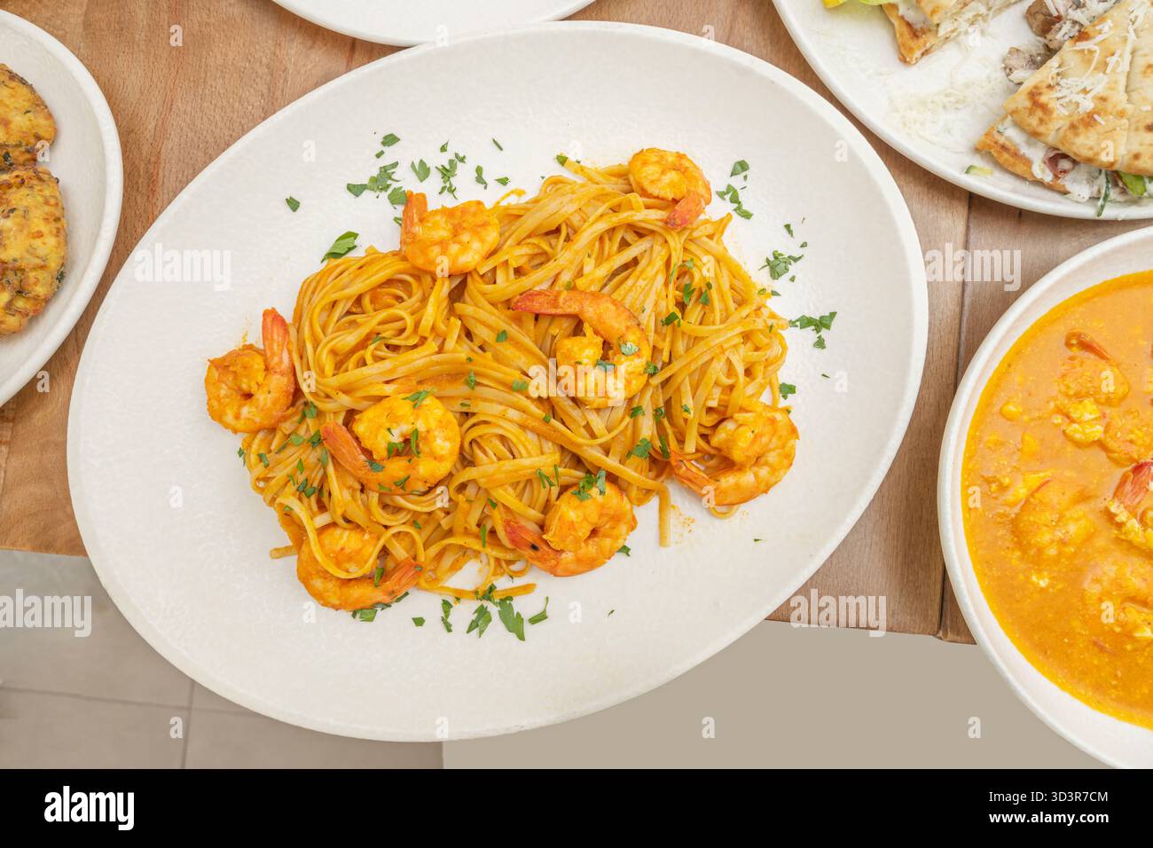 Dan Dan Dan Nudeln mit Garnelen, Sesampaste, Chili-Öl und gehacktem Schnittlauch in einer Marinara-Version Stockfoto