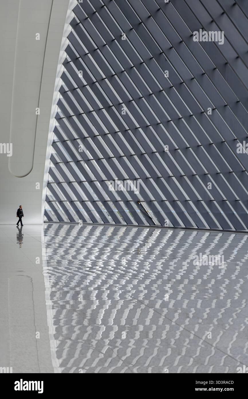 Chongqing, China - 13. Oktober 2025: Blick auf eine einsame Figur, die auf dem polierten Boden des Chongqing West Station läuft, das Licht wirft einen auffälligen Patte Stockfoto