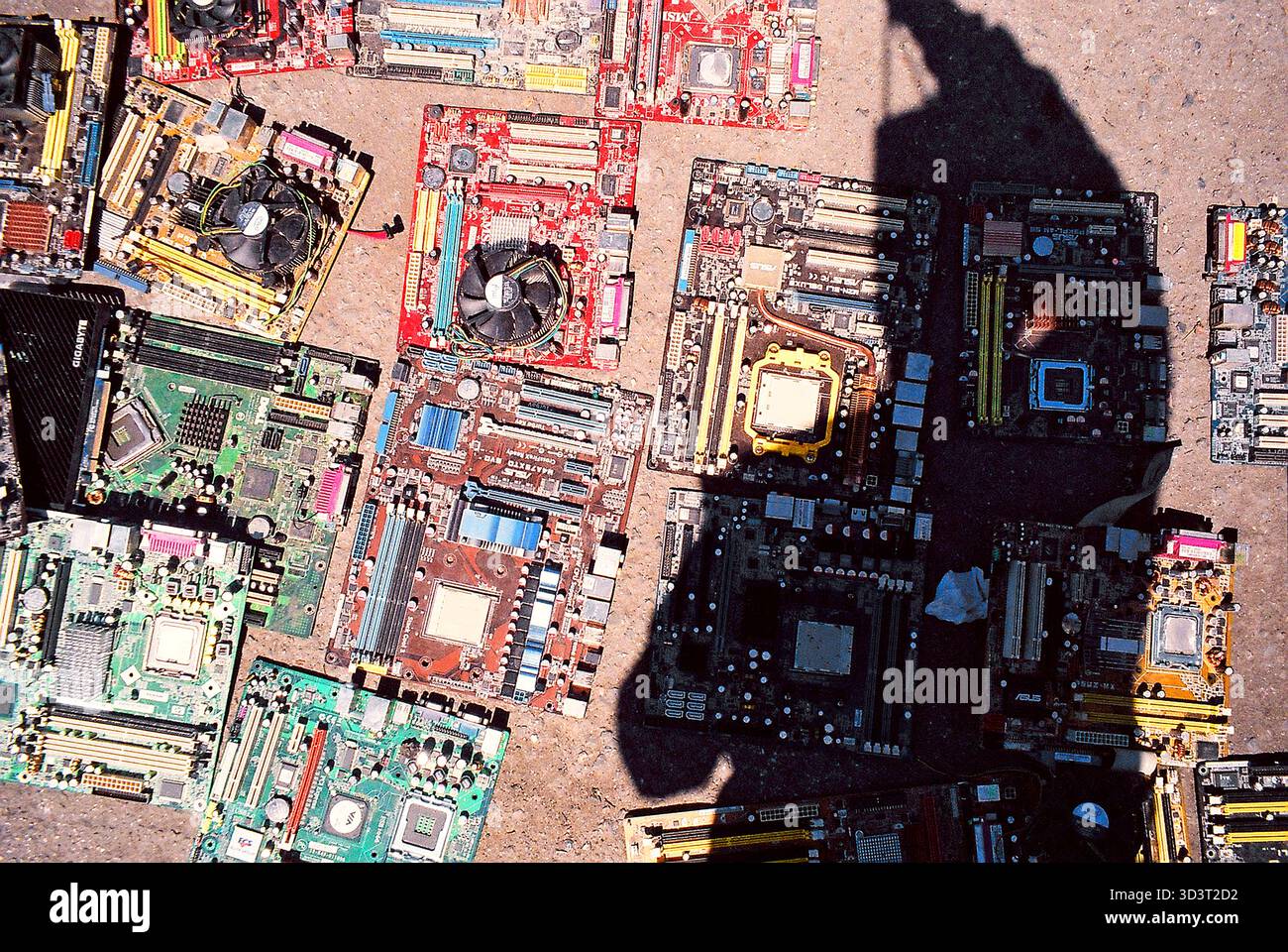 Leiterplatten von alten Computern liegen auf Beton auf einem Markt, der Schatten des Fotografen kreuzt sie, aufgenommen in analogen Momentaufnahmen. Stockfoto