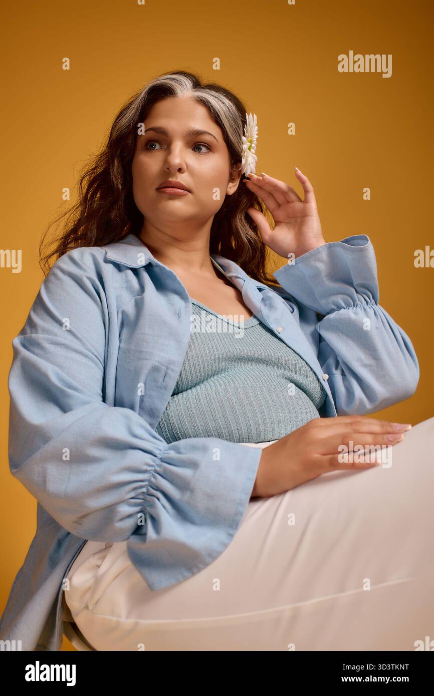 Eine junge Frau mit weißem Vorderkopf posiert anmutig in einem Studio und hebt ihre einzigartige Schönheit hervor. Stockfoto