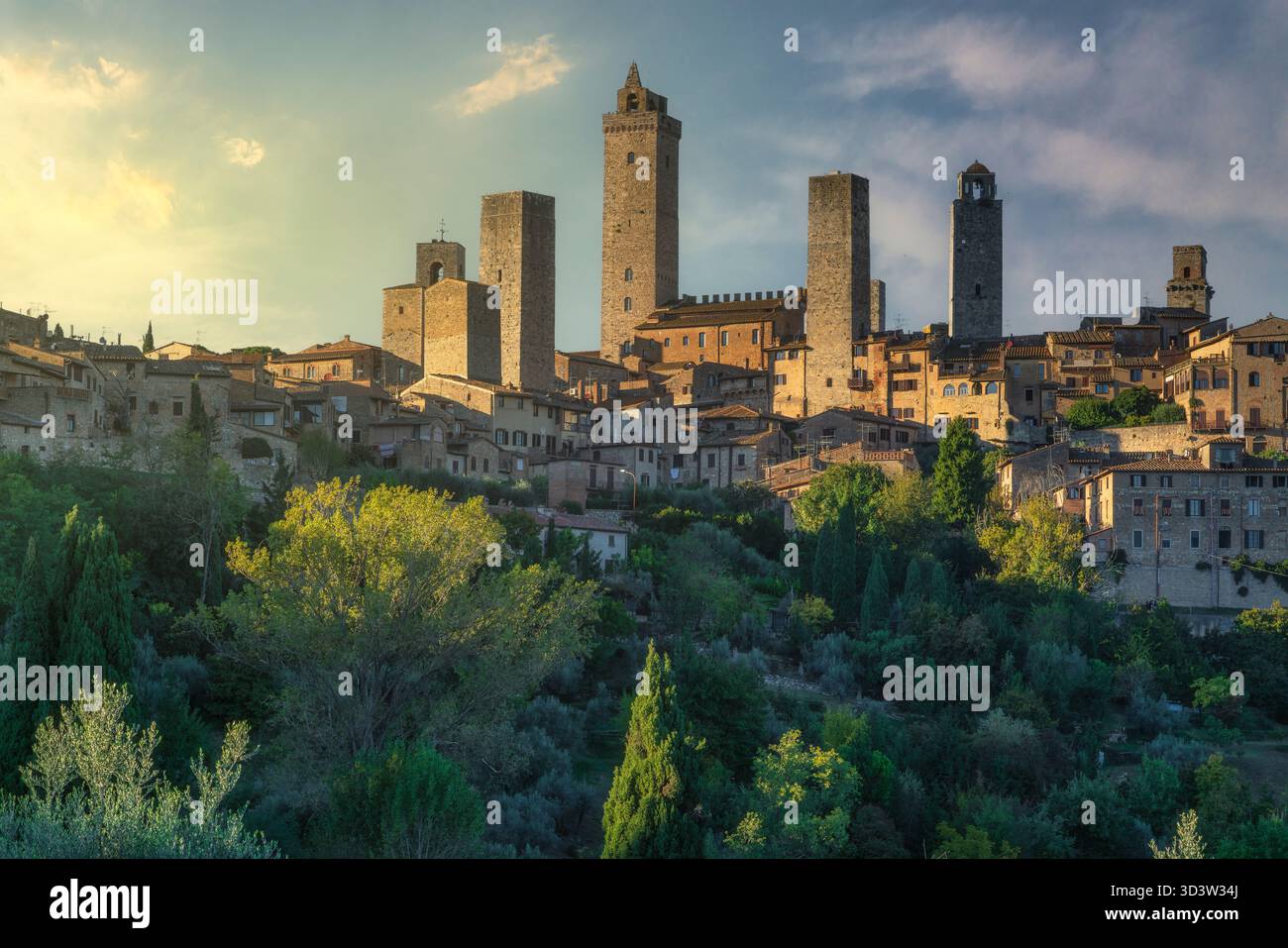 Dramatischer Blick auf den Sonnenuntergang über die mittelalterlichen Türme von San Gimignano, Toskana, Italien. Die historische Bergstadt leuchtet mit warmem Licht vor einem lebendigen Himmel. Stockfoto