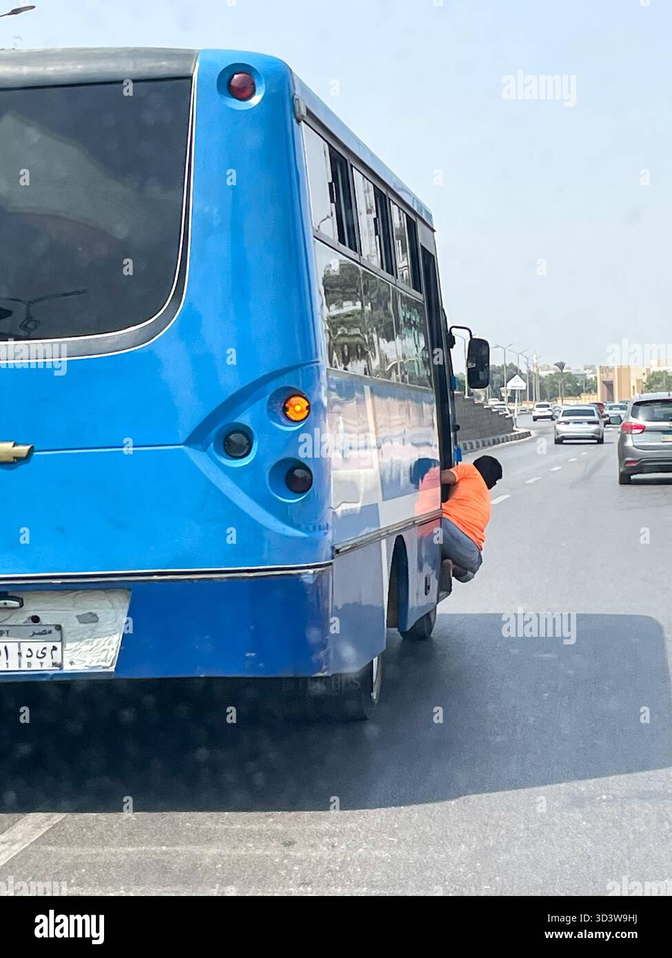Mann hängt an der Seite eines überfüllten ägyptischen öffentlichen Verkehrsbusses, Kairo, Ägypten - Smartphone-aufgenommenes Stockfoto