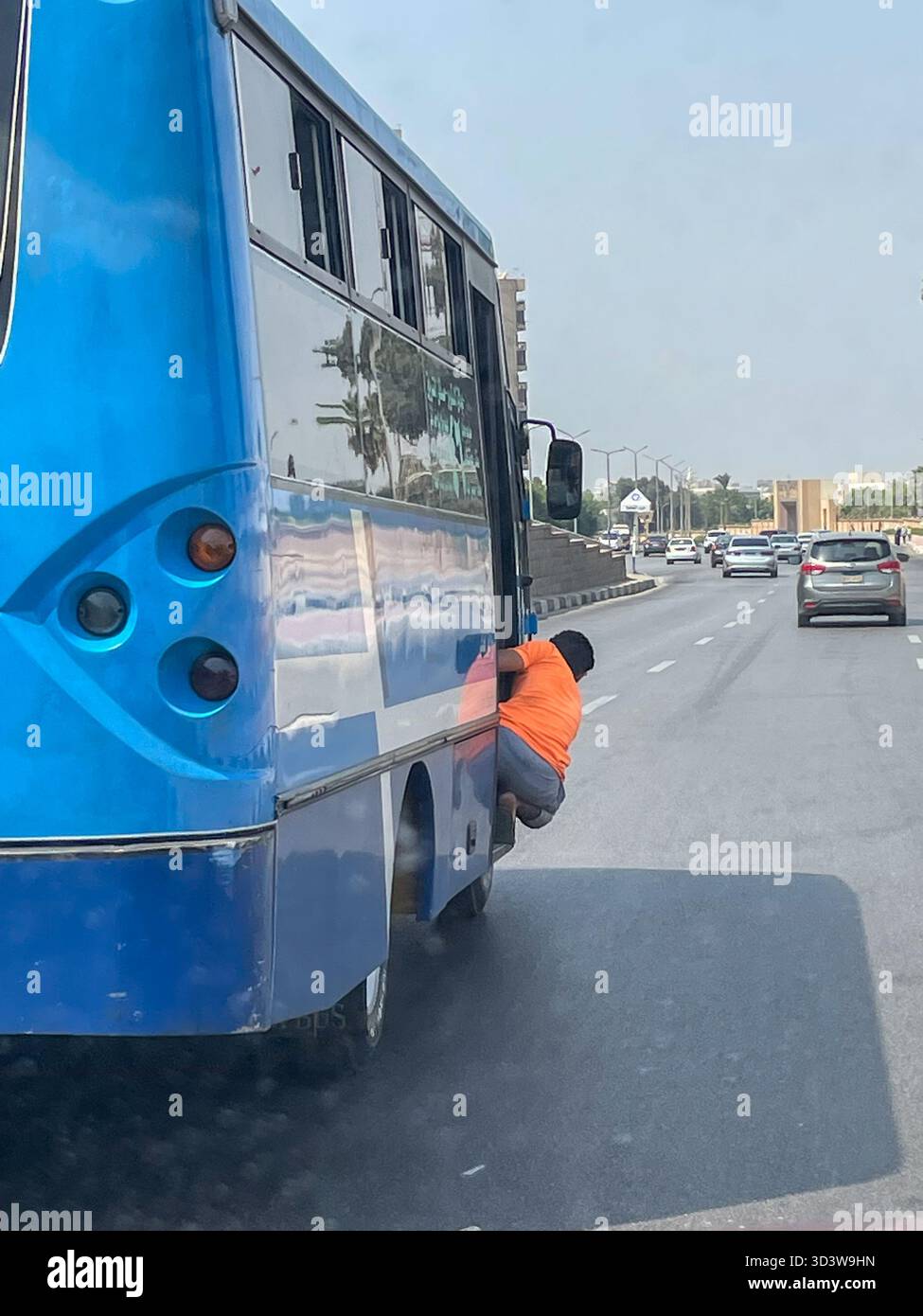 Mann hängt an der Seite eines überfüllten ägyptischen öffentlichen Verkehrsbusses, Kairo, Ägypten - Smartphone-aufgenommenes Stockfoto