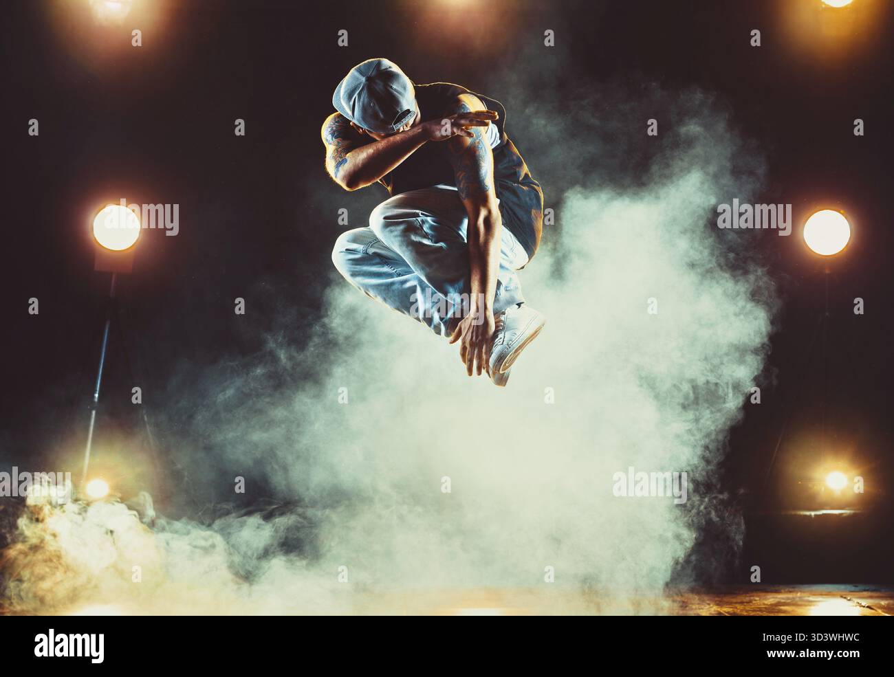 Junger Mann tanzt im Club mit Licht und Rauch. Tätowierung am Körper Stockfoto