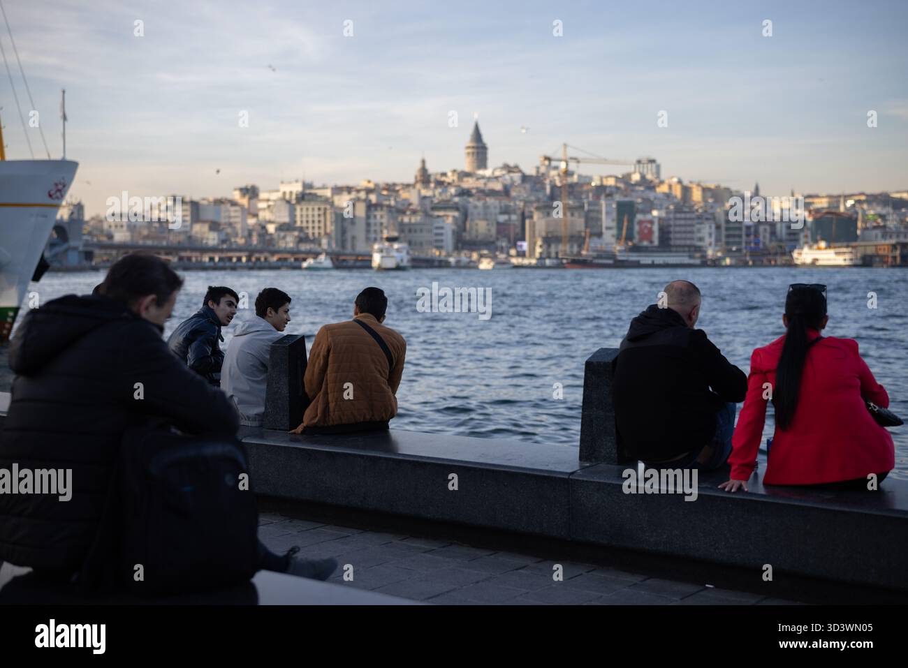 Fußgänger am Ufer des Goldenen Horns mit dem Galatenturm in der Ferne - Istanbul, Türkei. Stockfoto