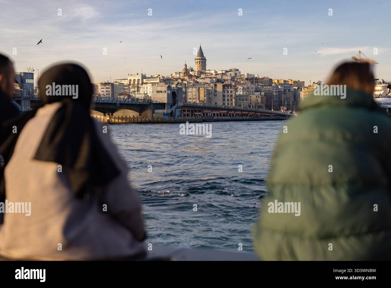 Fußgänger am Ufer des Goldenen Horns mit dem Galatenturm in der Ferne - Istanbul, Türkei. Stockfoto
