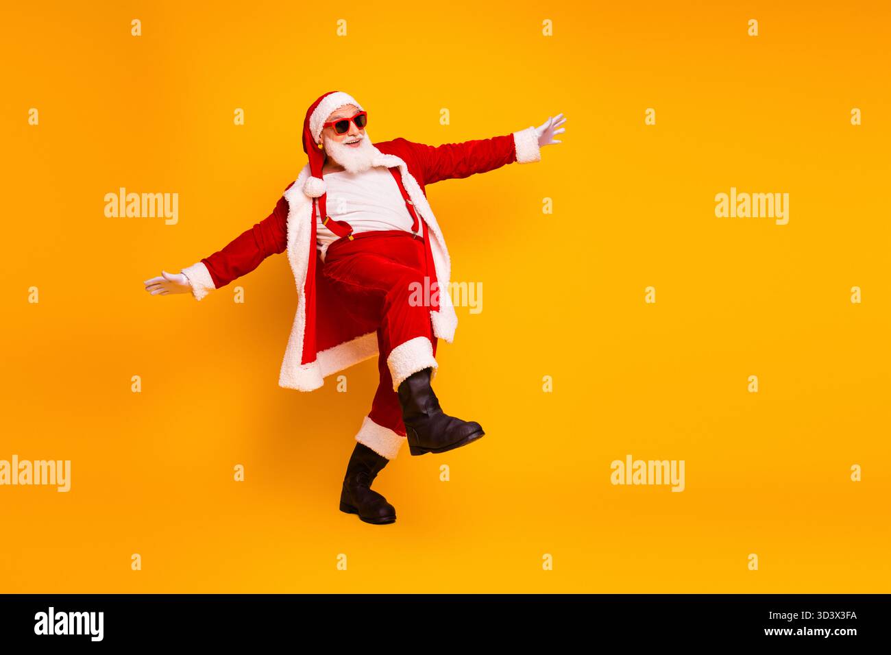 Weihnachtsmann in rotem Kostüm tanzt fröhlich gelber Hintergrund und verbreitet festliche Weihnachtsstimmung Weihnachtsfeiern saisonale Einkaufskampagnen Stockfoto