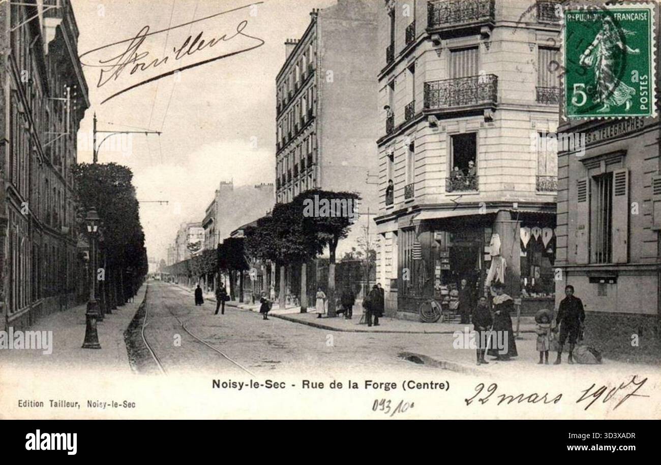 Dieses Bild aus dem Jahr 1907 zeigt die Rue de la Forge an der Kreuzung Carrefour in Noisy-le-SEC, Frankreich und bietet einen Einblick in das urbane Leben und die Architektur des frühen 20. Jahrhunderts. Stockfoto