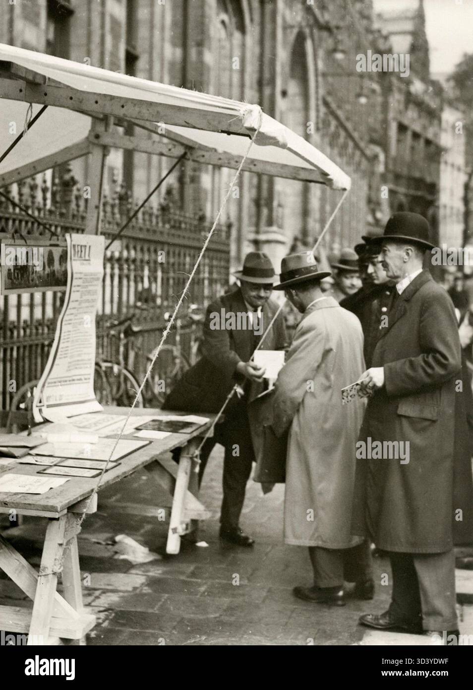 Ein Straßenverkäufer, der verschiedene Artikel verkauft, darunter Zeitungen, Bilder und Neuheiten. Niederlande, 1915-1935, Ort und exaktes Jahr unbekannt. Stockfoto