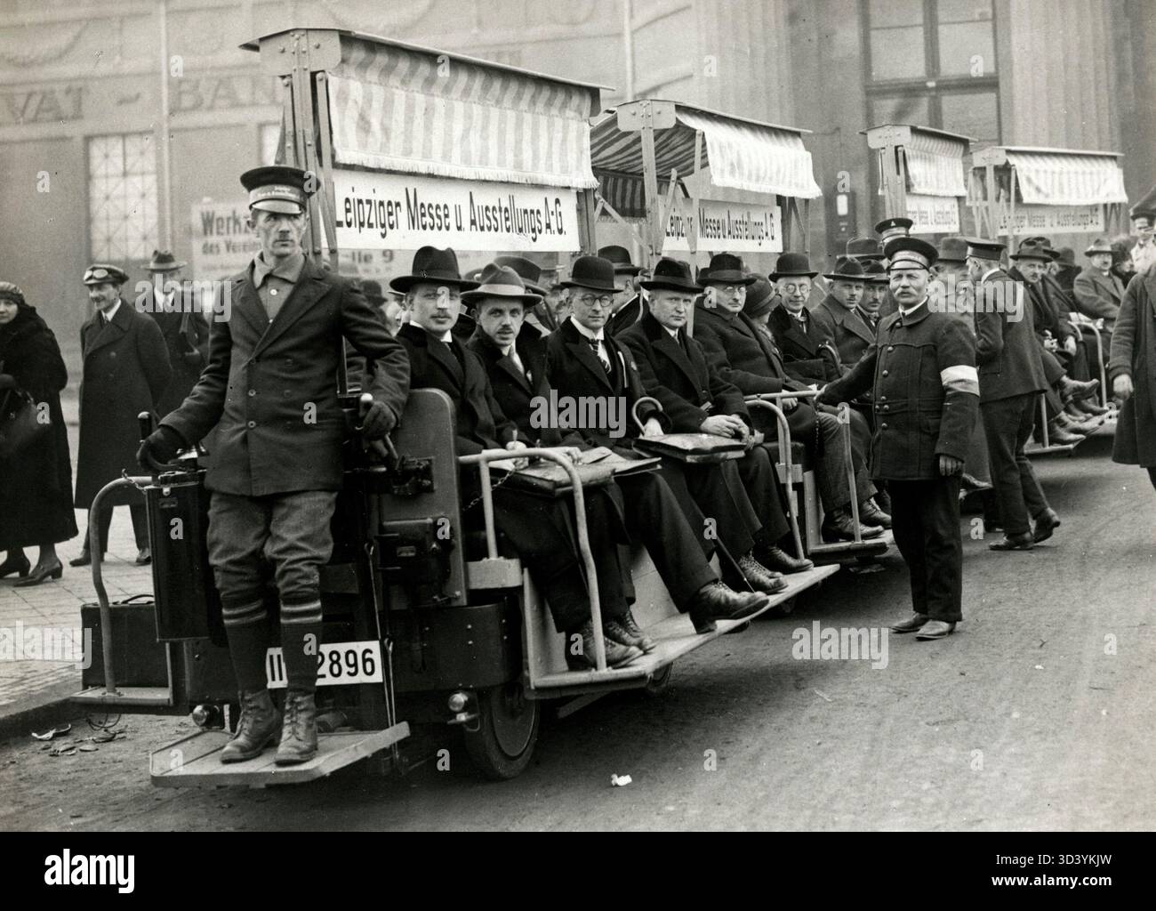 1925 werden die Besucher auf der Leipziger Messe in Leipzig mit einem elektrisch angetriebenen Wagenzug mit einem Fahrer auf dem Bahnsteig transportiert. Stockfoto