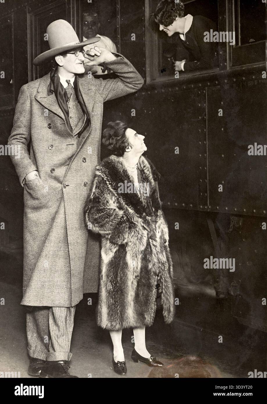 Der höchste Mann aus den USA, der sich mit einer durchschnittlich großen Frau in einem Pelzmantel an ein Zugabteil lehnt. Dieses Foto wurde 1920 in Hollywood, USA, aufgenommen. Stockfoto