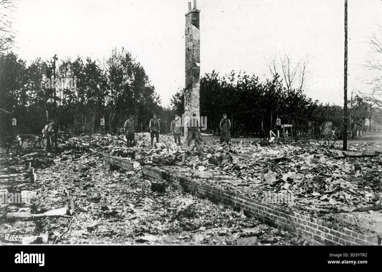 Einige niederländische Soldaten waren in den Überresten verbrannter Gebäude nach der Meuterei in der Harskamp-Kaserne auf der Veluwe, Niederlande, im Oktober 1918. Nur ein Schornstein steht noch. Stockfoto
