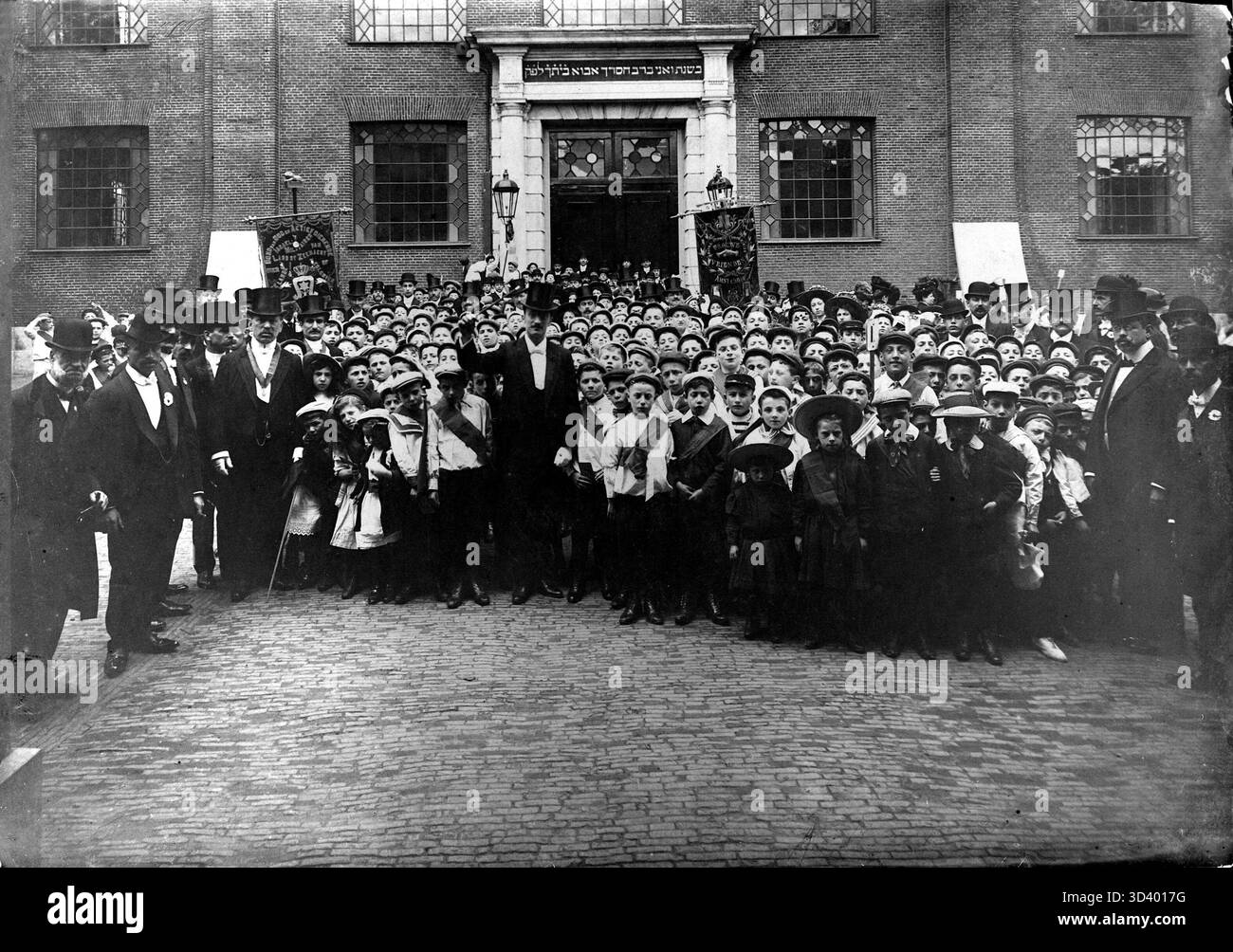 1910 führten Teilnehmer einer hebräischen Ballade eine Generalprobe auf dem großen Platz vor der Portugiesisch-israelischen Synagoge in Amsterdam durch. Der Dirigent und Komponist Victor Schlesinger steht im Mittelpunkt des Fotos. Stockfoto
