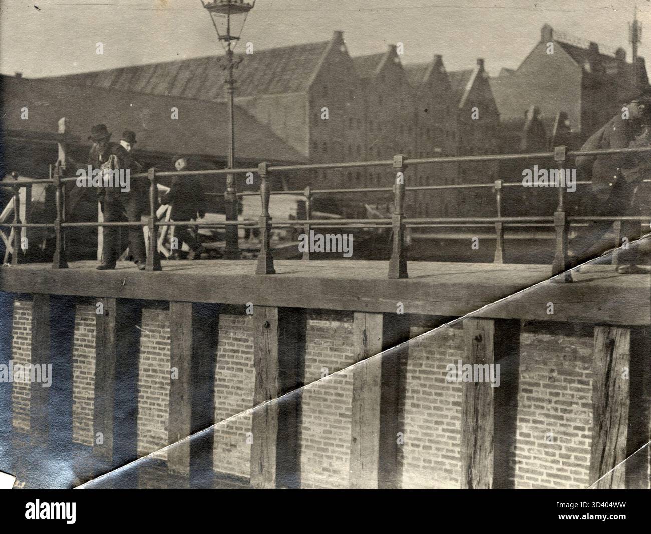 Ein Katzenfänger auf Bickerseiland, der über dem Geländer eines Kais hängt und nach vorbeifahrenden Wildkatzen Ausschau hält, um sie in Amsterdam zu fangen, 1911. Stockfoto