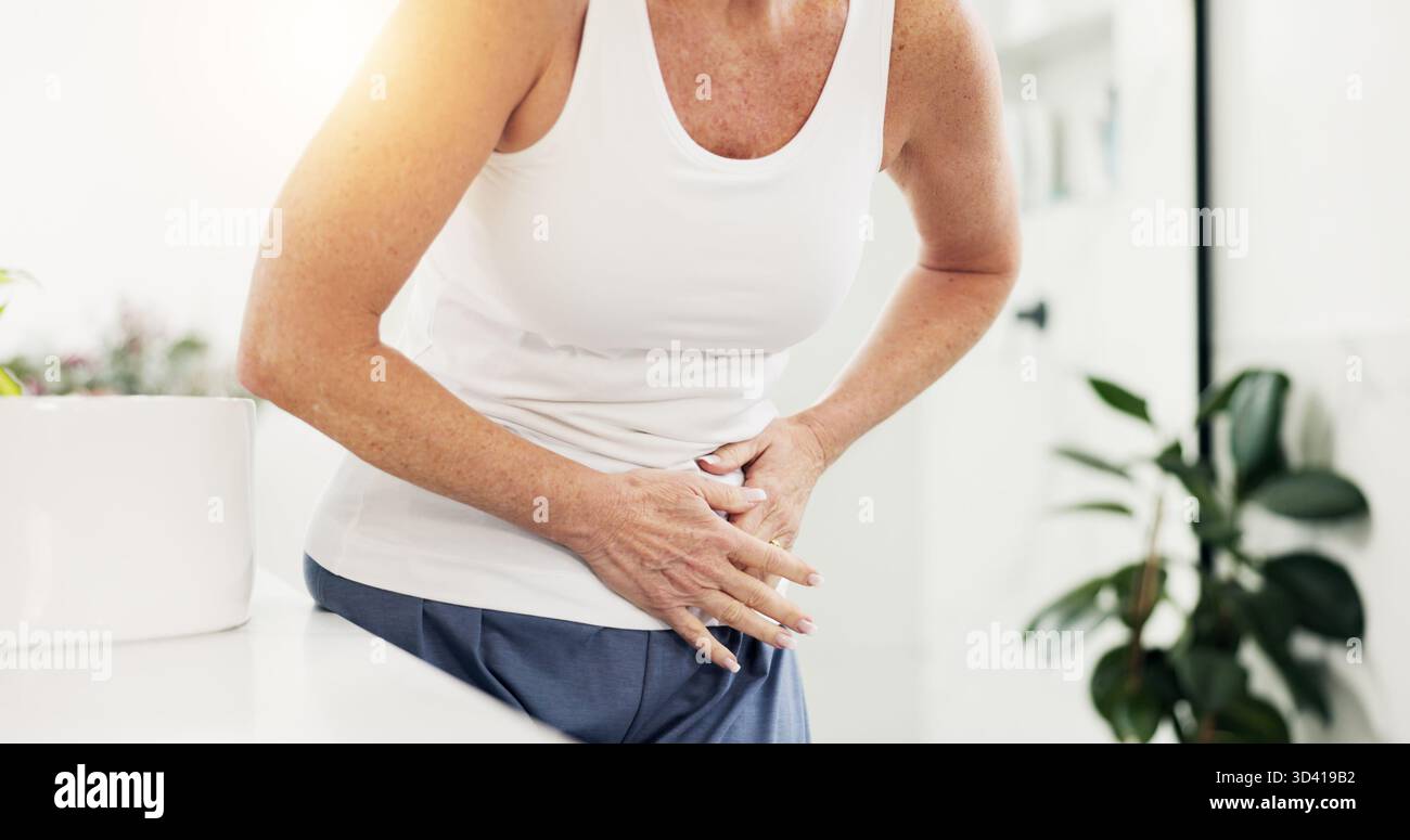 Hände, reife Frau und Magenschmerzen im Badezimmer mit Verdauungsstörungen, Verstopfung und Reizdarm-Symptomen. Heim, Kranke und Bauchblähungen morgens mit Stockfoto