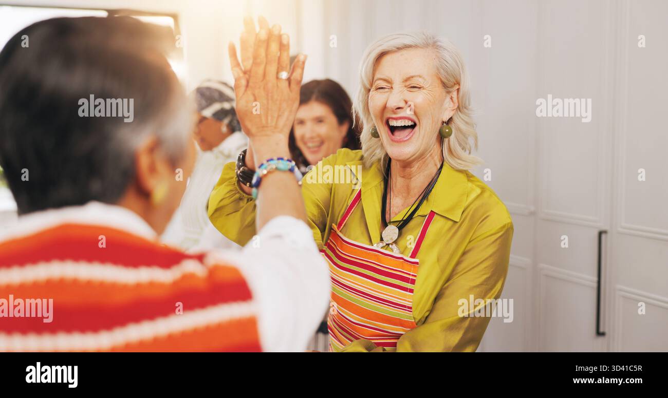 Kochkurs, Senior Friends und High Five in der Küche für Rezepterfolg, kulinarische Fähigkeiten und Verbundenheit. Ruhestand, alte Frauen und Feier zum Essen Stockfoto