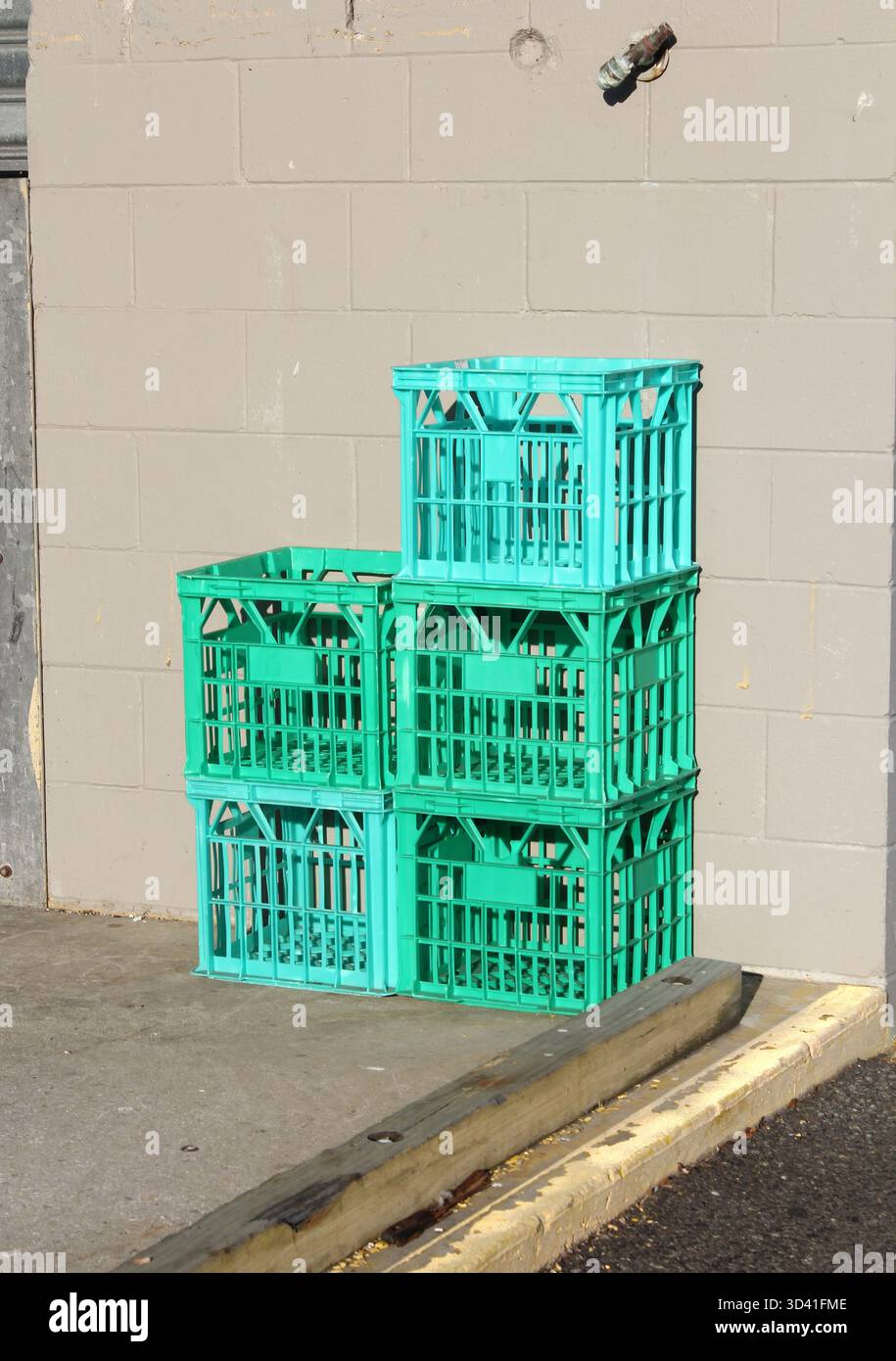 Stapel türkisgrüner Milchkisten an einer grauen Ziegelwand Stockfoto