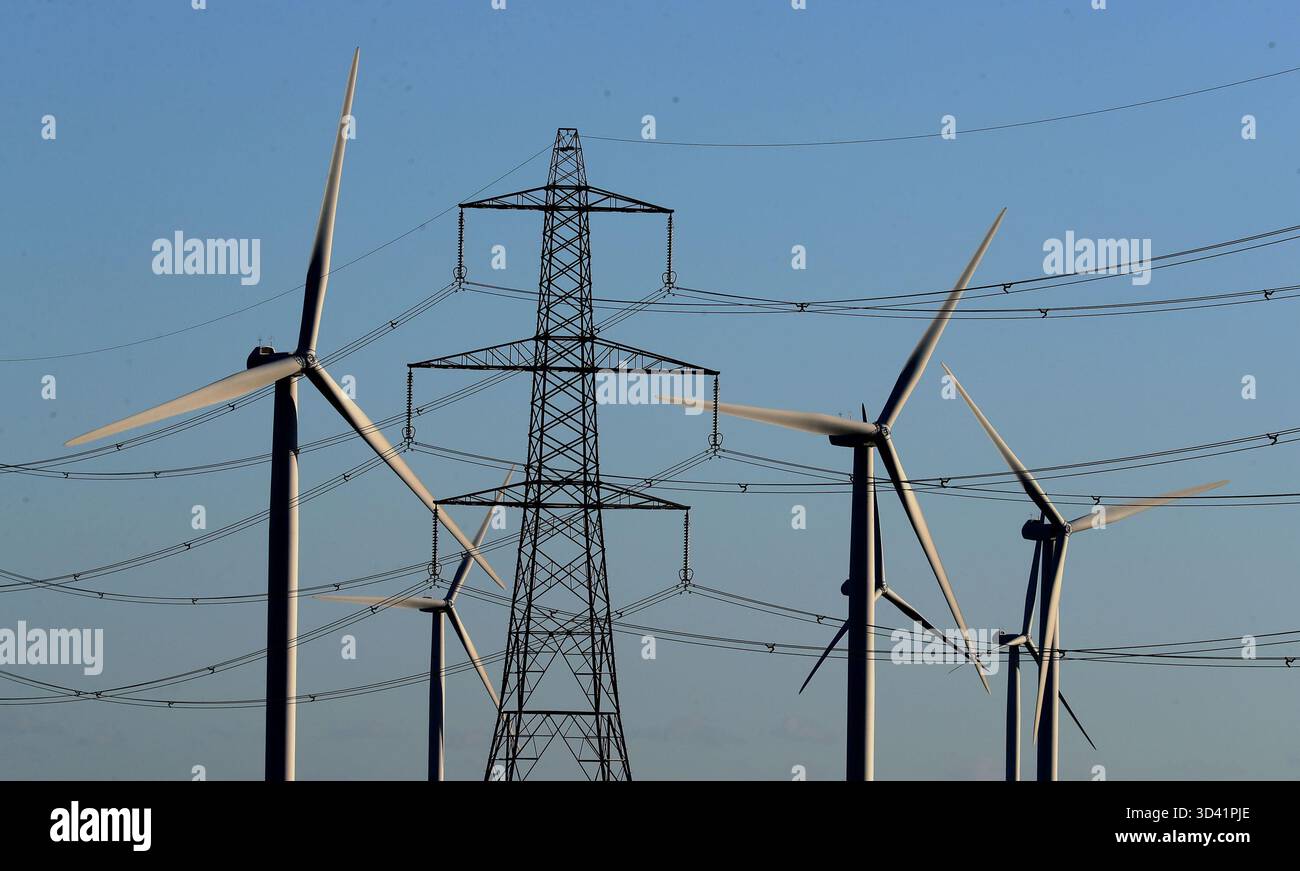 Aktenfoto vom 28./12/17 mit Blick auf den Windpark Little Cheyne Court zwischen bestehenden Strommasten auf dem Romney Marsh in Kent. Die Regierung sollte die Energierechnungen senken, indem sie Subventionen für erneuerbare Energien abschafft, die Systemkosten senkt und Effizienzstandards für Vermieter durchsetzt, fordert ein Think Tank. Ausgabedatum: Samstag, 8. November 2025. Stockfoto